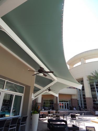 Green canopy over outdoor seating area with ceiling fans.