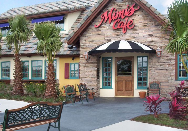 Mimi's Cafe exterior with stone facade, black and white awning, and palm trees.