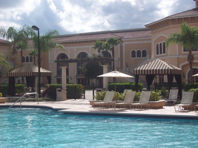 Swimming pool with lounge chairs and cabanas in front of a resort building.