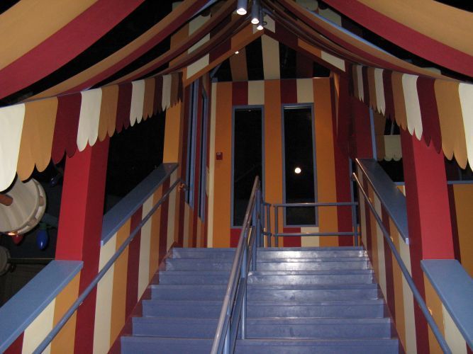 Staircase leading to a brightly colored circus-themed doorway, with red, yellow, and orange accents.