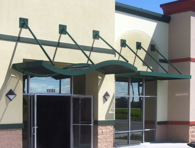 Green awning over building entrance. Beige building with glass windows.