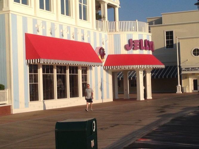 A person walks in front of a building with red awnings and striped blue and white walls that reads “JUMBO.”