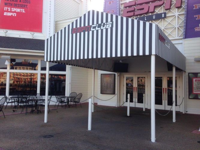 ESPN Club entrance with black and white striped awning, white pillars, and outdoor seating.