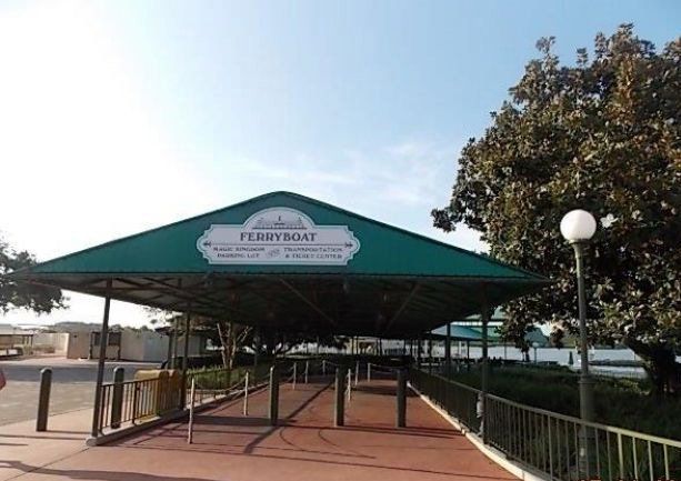 Covered ferryboat loading area, green roof, sign, concrete path, Disney World.