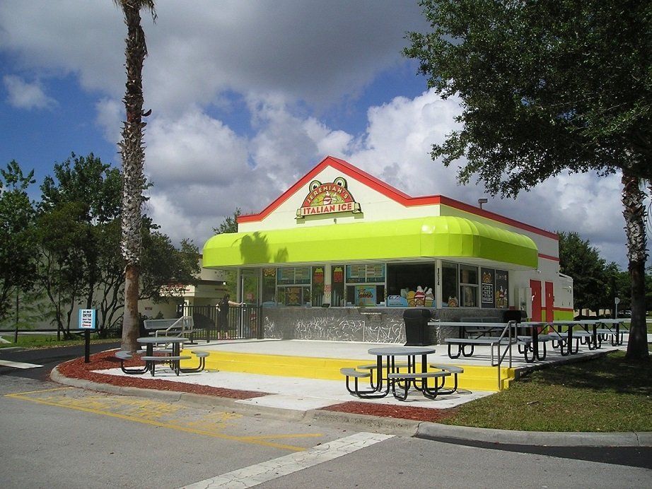 Ice cream shop with a lime green awning, picnic tables, and a red roof.