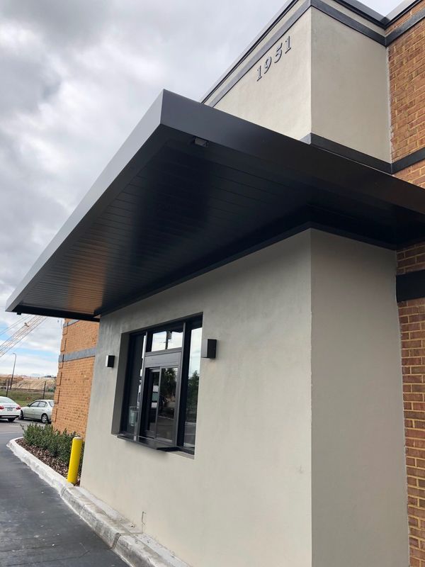 Drive-thru window of a building with a black awning and a sign with the number 1931.