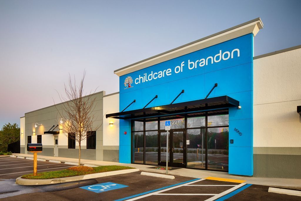 Childcare of Brandon building with blue and white exterior; entrance with awnings, parking and wheelchair symbol.