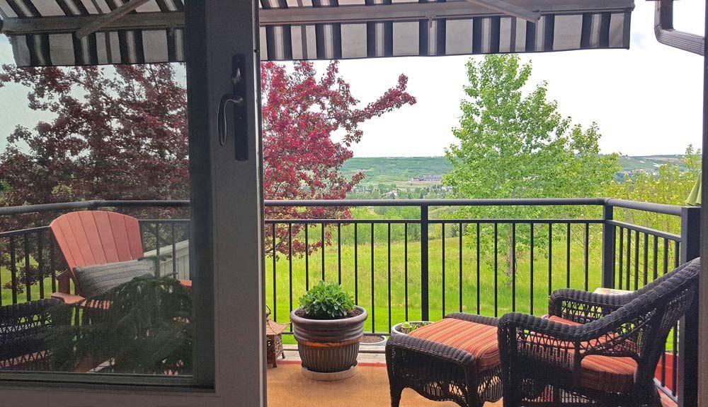 Patio with wicker furniture, a red chair, and a view of green fields and trees.