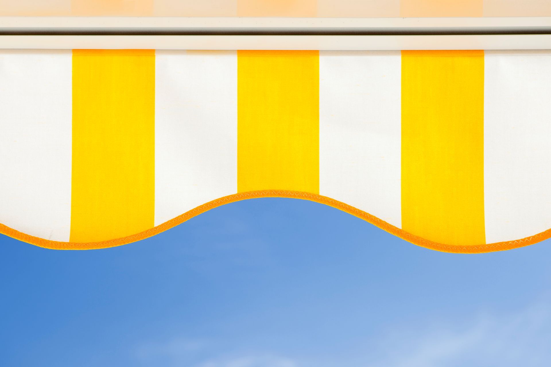 Yellow and white striped awning against a bright blue sky.