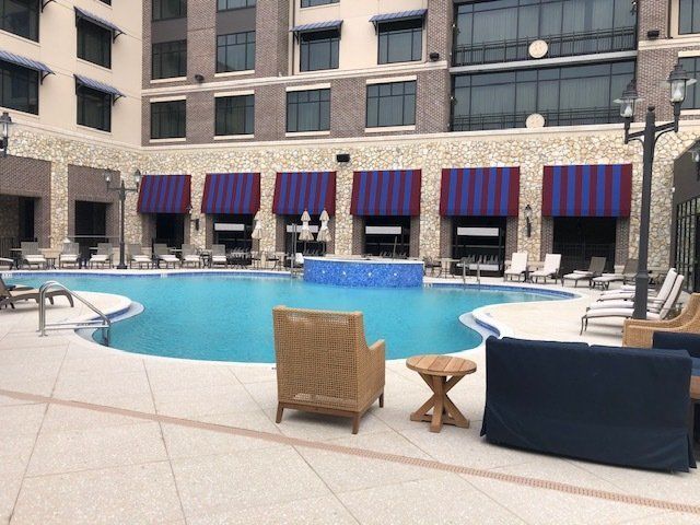 Swimming pool with loungers, a wall with awnings, and a building in the background.