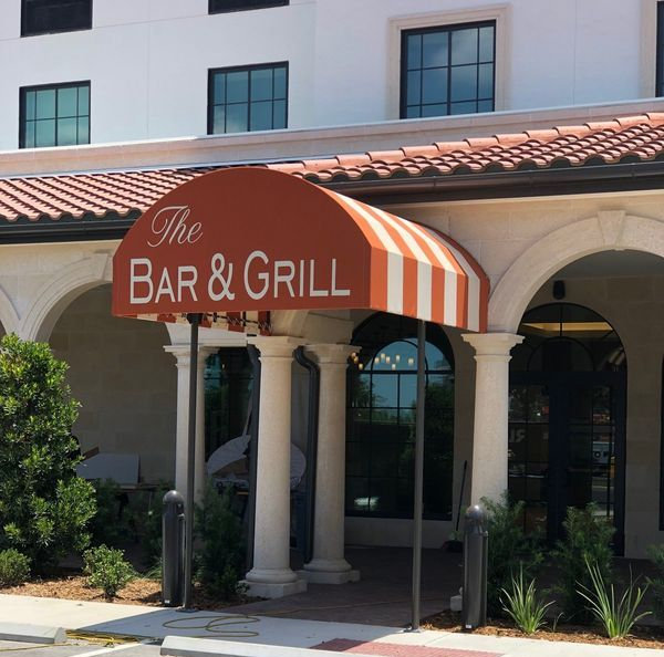 A striped orange and white awning shades a storefront; tan building exterior.