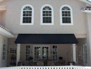 Residential patio area featuring a large black retractable awning. Residential patio area featuring a large black retractable awning.