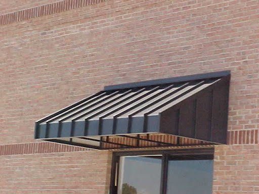 Dark metal awning over a storefront door against a brick wall.