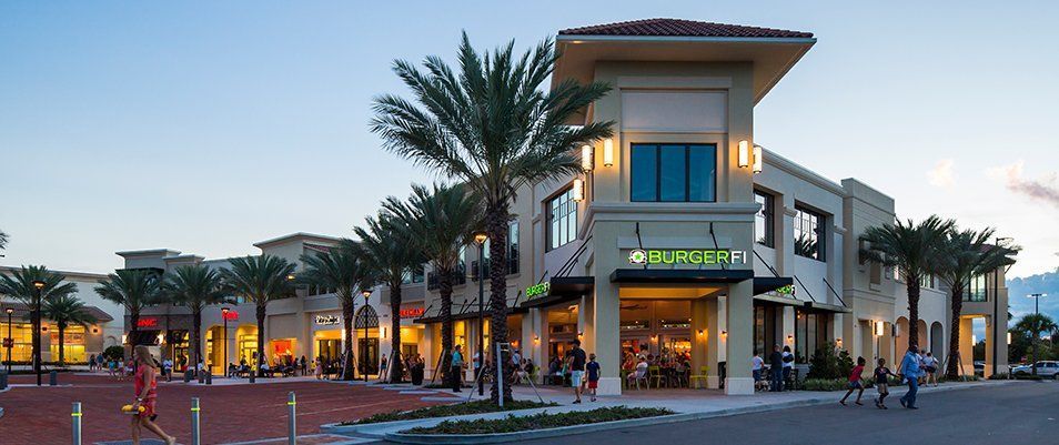 Exterior of a restaurant, Brio Italian Grille, at a shopping center with palm trees and people.