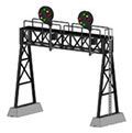Two green signal lights on a metal railroad crossing gantry over a track.
