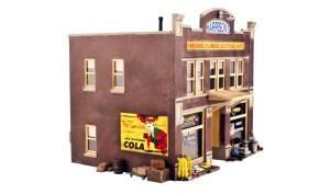 Miniature brown storefront model with a red cola sign and small details on the sidewalk.