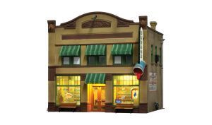 Small vintage storefront with green awnings, warm lit windows, and a sign above the door