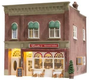 Miniature two-story brick café with green awnings, lit storefront, outdoor tables, and red-framed windows