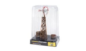 Toy oil derrick model in clear display case, with brown tower and red top.