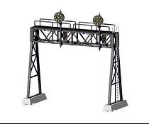 A railroad signal bridge with two mounted signal lights on black steel supports and concrete bases.