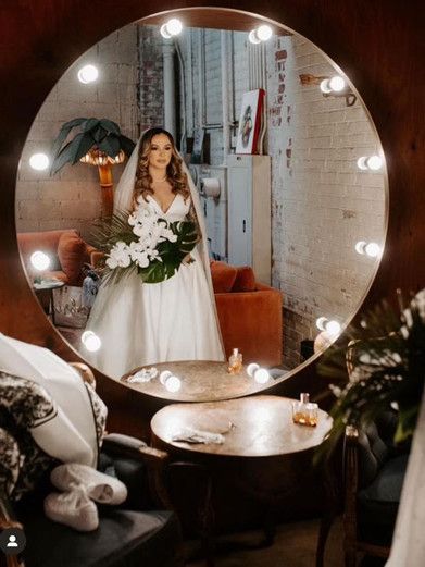 A bride is taking a picture of herself in a large mirror.