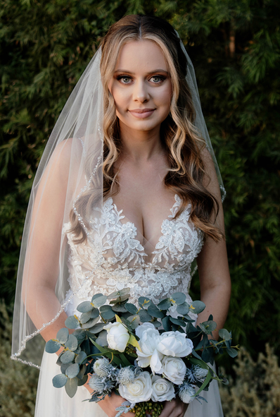 The bride is wearing a veil and holding a bouquet of flowers.