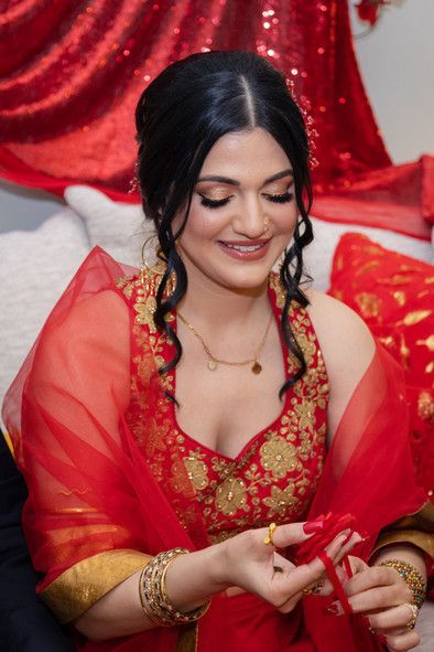 A woman in a red and gold dress is sitting on a couch holding a red ribbon.