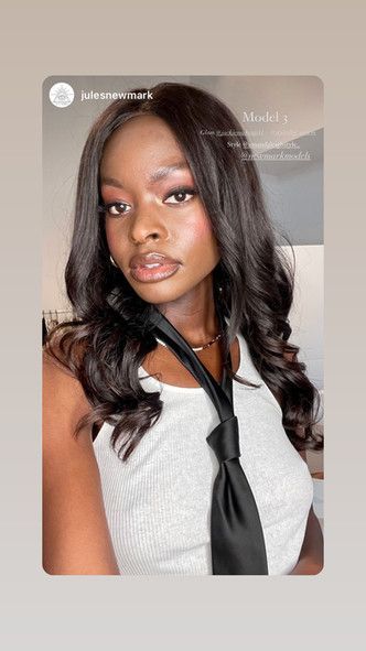 A woman is wearing a white tank top and a black tie.