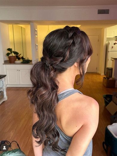 A woman is wearing a braided ponytail in a living room.