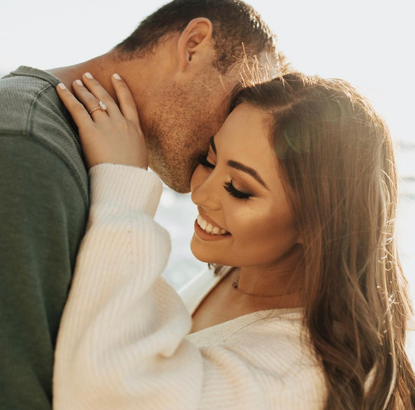 A man and a woman are kissing and the woman is wearing a ring on her finger.