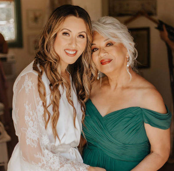 A woman in a white robe and a woman in a green dress are posing for a picture