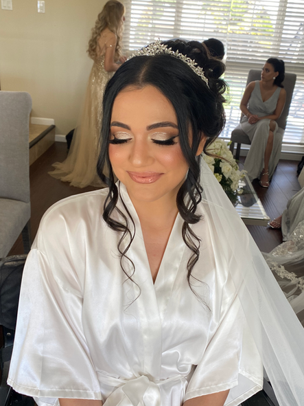 A woman in a white robe and veil is getting ready for her wedding.