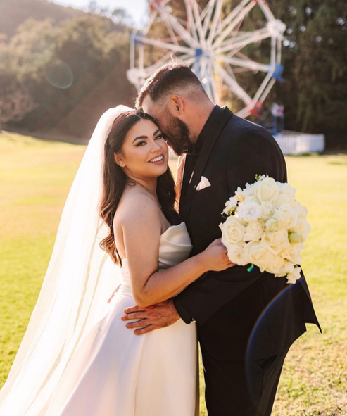 A bride and groom are posing for a picture in front of a ferris wheel.
