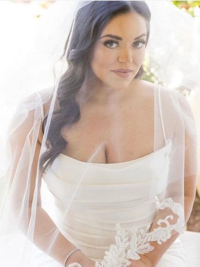 A woman in a white dress and veil is sitting down.