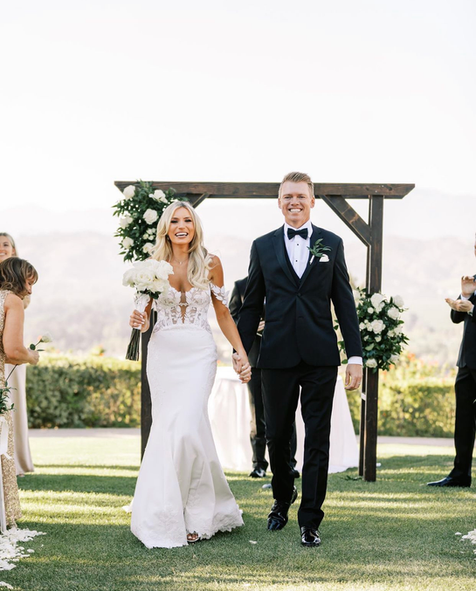A bride and groom are walking down the aisle at their wedding holding hands.