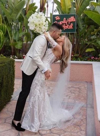 A bride and groom kissing in front of a sign that says everly hills hotel