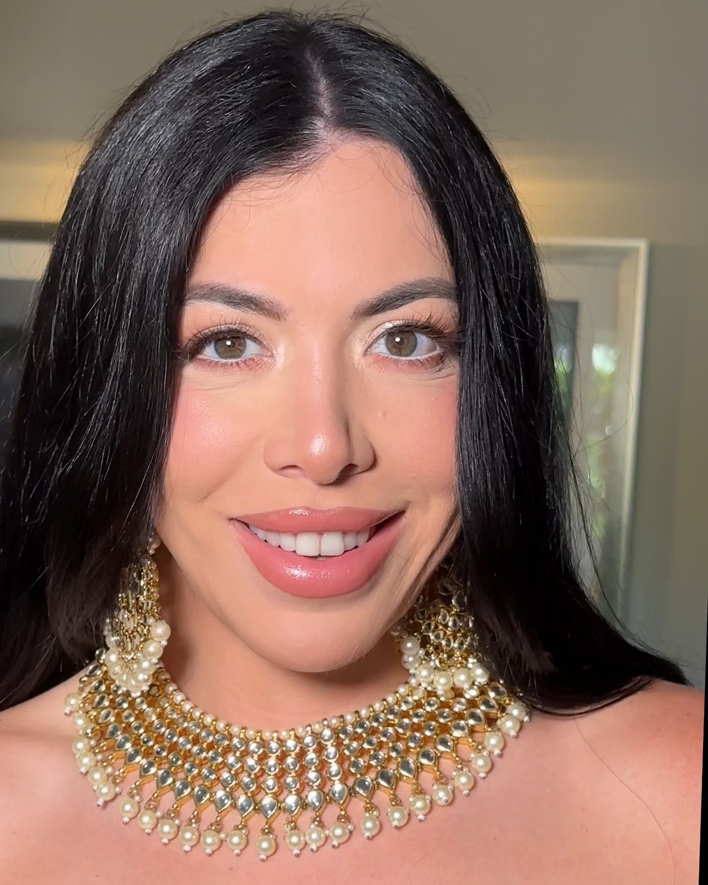 A woman wearing a necklace and earrings is smiling for the camera.
