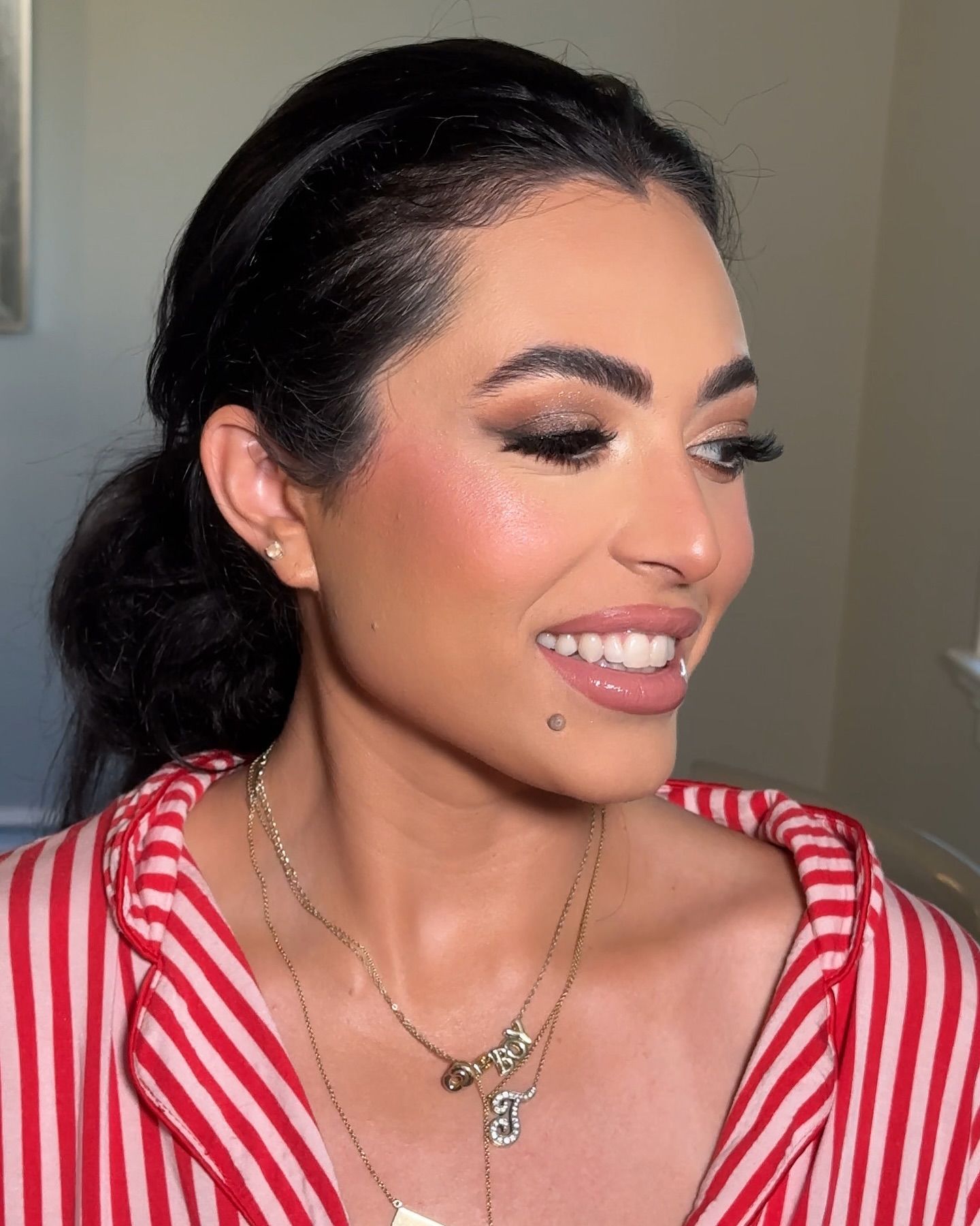 A woman wearing a red and white striped shirt and a necklace is smiling.