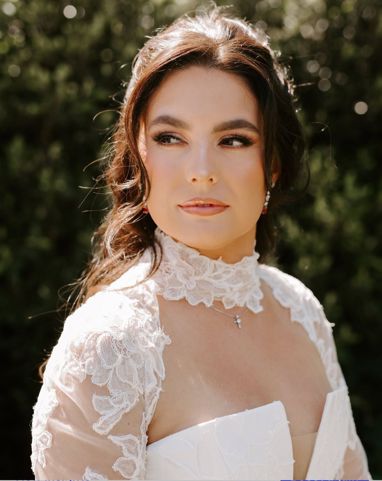 A bride and her bridesmaid are standing next to each other on a lush green field.