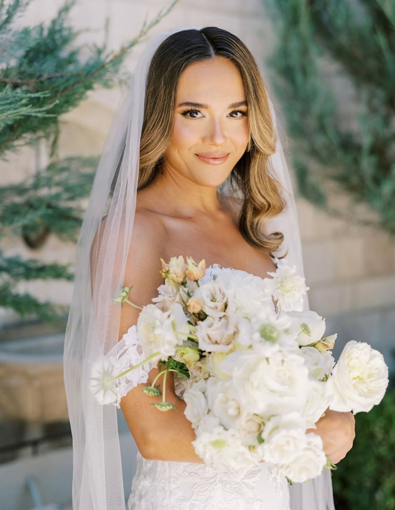 The bride is wearing a veil and holding a bouquet of flowers.
