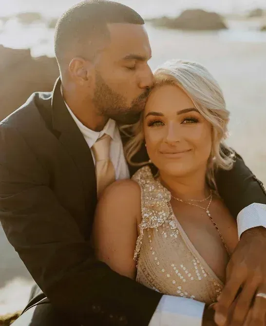 A man in a suit and tie is kissing a woman on the cheek.