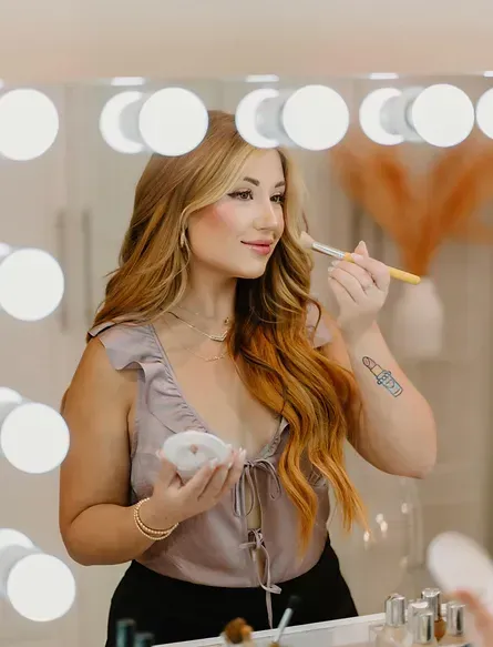 A woman is applying makeup in front of a mirror.