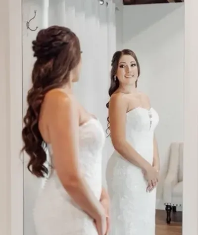 A woman in a white dress is standing in front of a mirror.