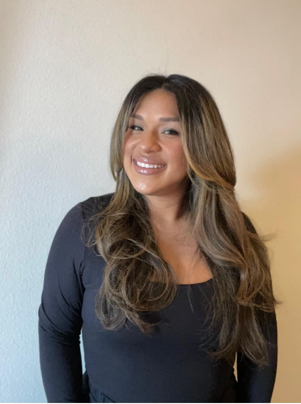 A woman with long hair is wearing a black shirt and smiling.