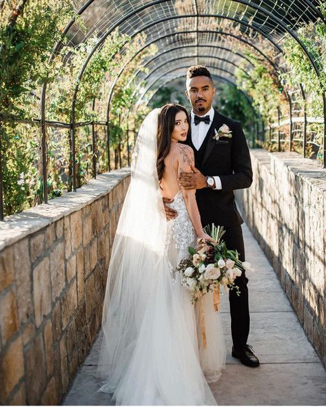 A bride and groom are posing for a picture in a greenhouse.
