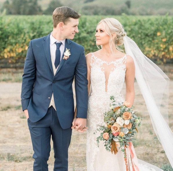 A bride and groom are holding hands in a field.
