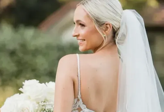 The bride is wearing a veil and holding a bouquet of flowers.