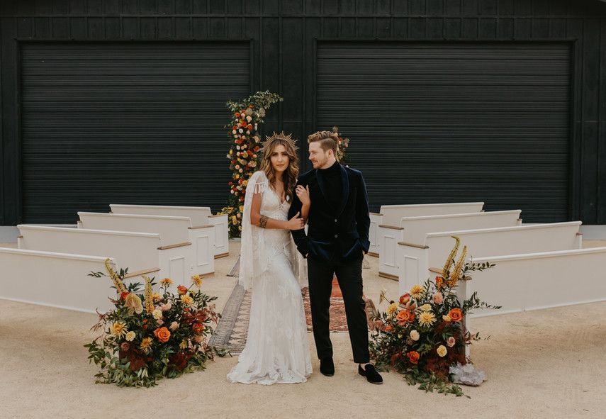 A bride and groom are standing in front of a black garage door.