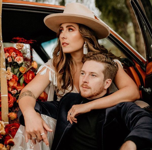 A woman in a hat is sitting next to a man in a car
