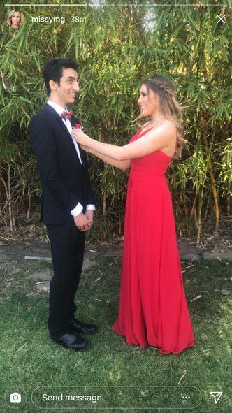 A man in a suit and a woman in a red dress are standing next to each other.
